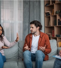 Angry couple arguing on a couch during a therapy session