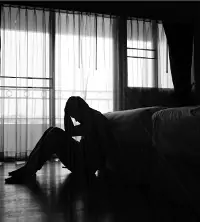 A man sitting in the dark and dealing with depression, needing Depression Treatment in East Peoria IL