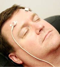 A man with his eyes closed and electrodes on his head, receiving Peoria Neurofeedback Treatment