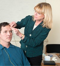 Woman attaching electrodes to a man's scalp during Peoria Neurofeedback