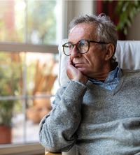 A man sadly looking out the window and contending with depression, needing Depression Treatment in Washington IL